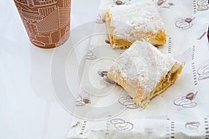 Two sweet strudel near the cardboard cup.