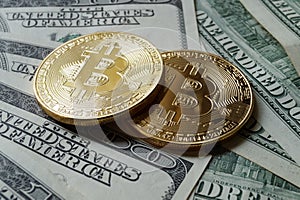 Two symbolic coins of bitcoin on banknotes of one hundred dollar