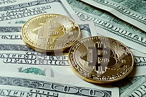 Two symbolic coins of bitcoin on banknotes of one hundred dollar