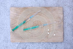 Two syringes on a cutting board Grey tile background