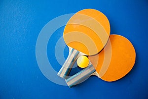 Two table tennis or ping pong rackets and balls on a blue table