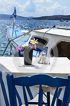 Two tables and chairs in a cozy restaurant on the embankment of the old port in the Greek city of Fira.