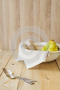 Two tablespoons on background of pears in bowl