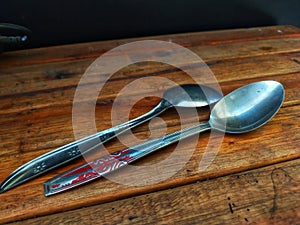 two tablespoons lying side by side on a wooden table