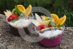 Two takeaway acai bowls with fresh fruit