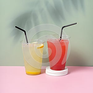 Two takeaway glasses of summer drinks with ice. Lemonade on coloured background