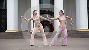 Two talented dancers moving simultaneously stepping aside performing Indian dance outdoors. Wide shot portrait of