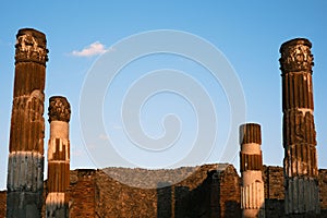 two tall columns are shown in an old ruins setting with some clouds