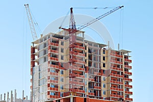 Two tall cranes and brick building under construction