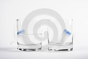 Two tampons for menstruation in a glass cup with and without water. tampon absorbency test. new tampon for critical days