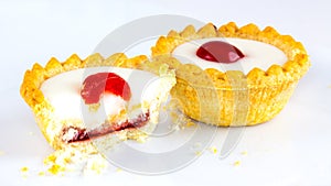Two Bakewell Tarts with white icing and a red cherry.