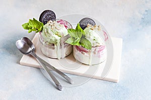 Two Tasty homemade multicolored popsicles ice cream with mint and chocolate cookies leaves in a glass jars