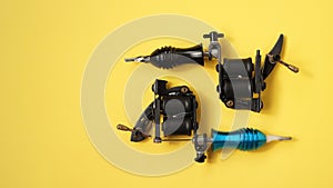 Two tattoo machines on a yellow background