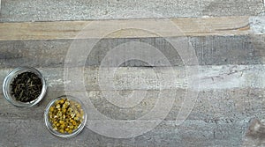 Two tea cups in glass with black tea and chamomile tea at natural wooden background