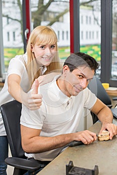 Two technicians in dental lab showing thumbs up