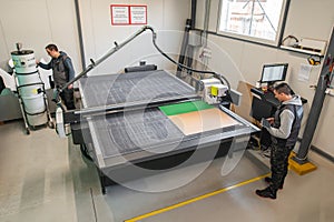 Two technicians works on CNC computer numerical control cutting machine