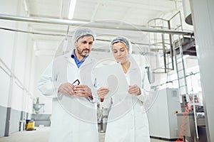 Two technologists in lab coats and masks at the factory.