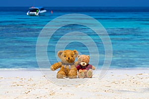 Two TEDDY BEAR brown color sitting on the beautiful beach with b