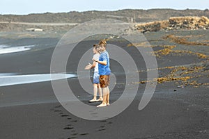 Two teen boys have fun at a black volcanic beach