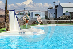 Two teen boys jump into the pool
