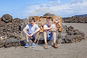 Two teen boys sitting on a rock and have a rest