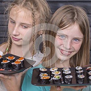 Two teen girl with sushi roll , teenage girls eating japanese sushi