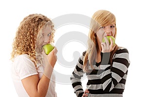 Two teen girlfriends eating green apples