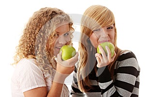 Two teen girlfriends eating green apples