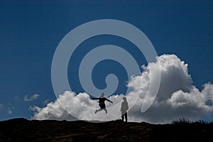 Two Teen Girls Jumping on the Top of Mountain