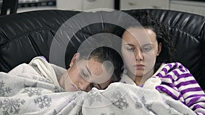 Two teen girls in pijamas sitting on the couch