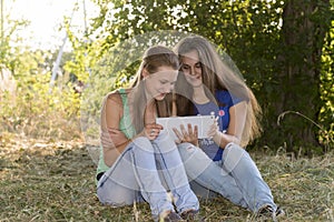 Two teen girls with your Tablet-PC in nature