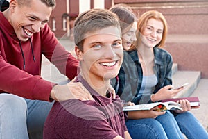 Two teenage boys having fun while studing against girls near university