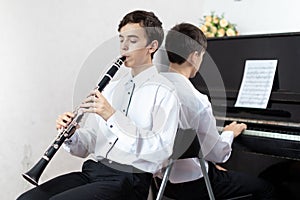 Two teenage boys play piano in class or at home .