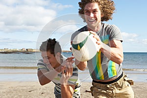 Two Teenage Boys Playing Rugby On Beach