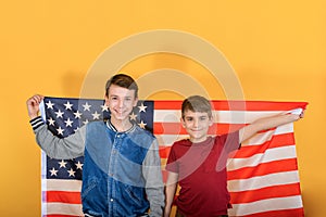 Two teenage brothers are standing against the backdrop of the American flag, young scouts are patriots