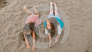 Two teenage children are lie on the beach.