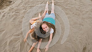 Two teenage children are lie on the beach.