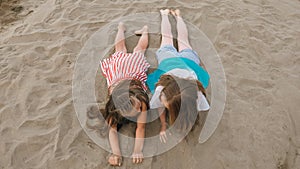 Two teenage children are lie on the beach.