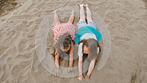 Two teenage children are lie on the beach.