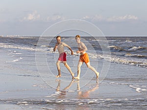 Two teenage friends and brothers enjoy jogging along the beach