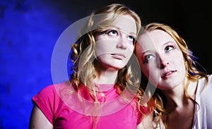 Two teenage girls on blue background looking up