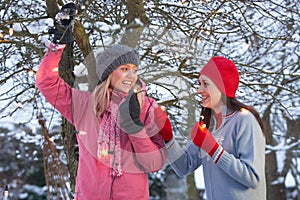 Two Teenage Girls Hanging Fairy Lights