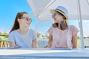 Two teenage girls in headphones listening music on smartphone, having fun