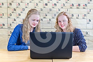Two teenage girls looking at computer in chemistry lesson