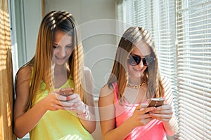 Two teenage girls looking in their gadgets