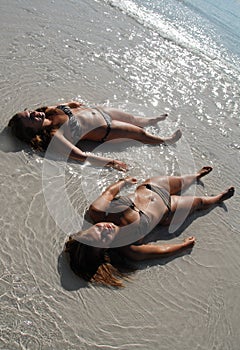 Two teenage girls lying on the beach
