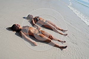 Two teenage girls lying on the beach