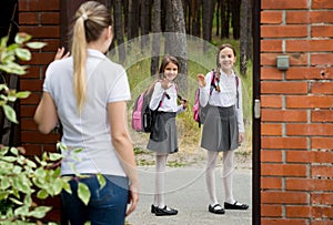 Two teenage girls in school uniform leaving home to school