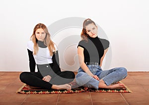 Two teenage girls sitting on oriental carpet