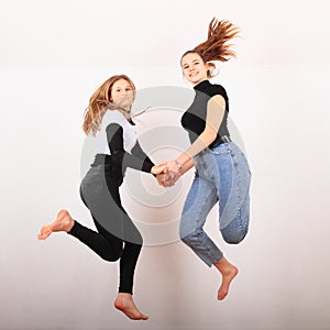 Two teenage girls smiling and jumping friends